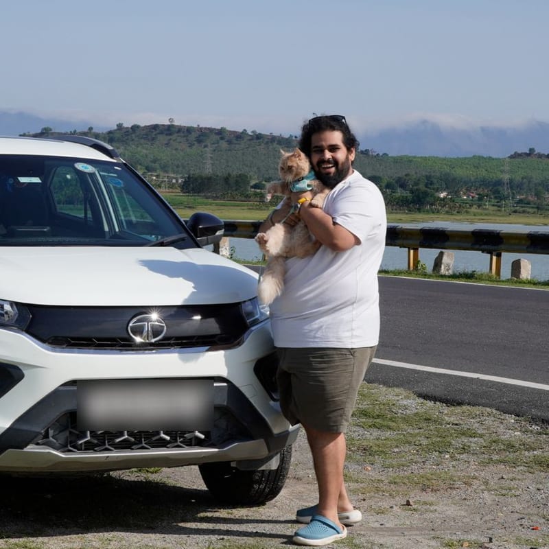 Alabhya holding Bailey by the car on a road trip